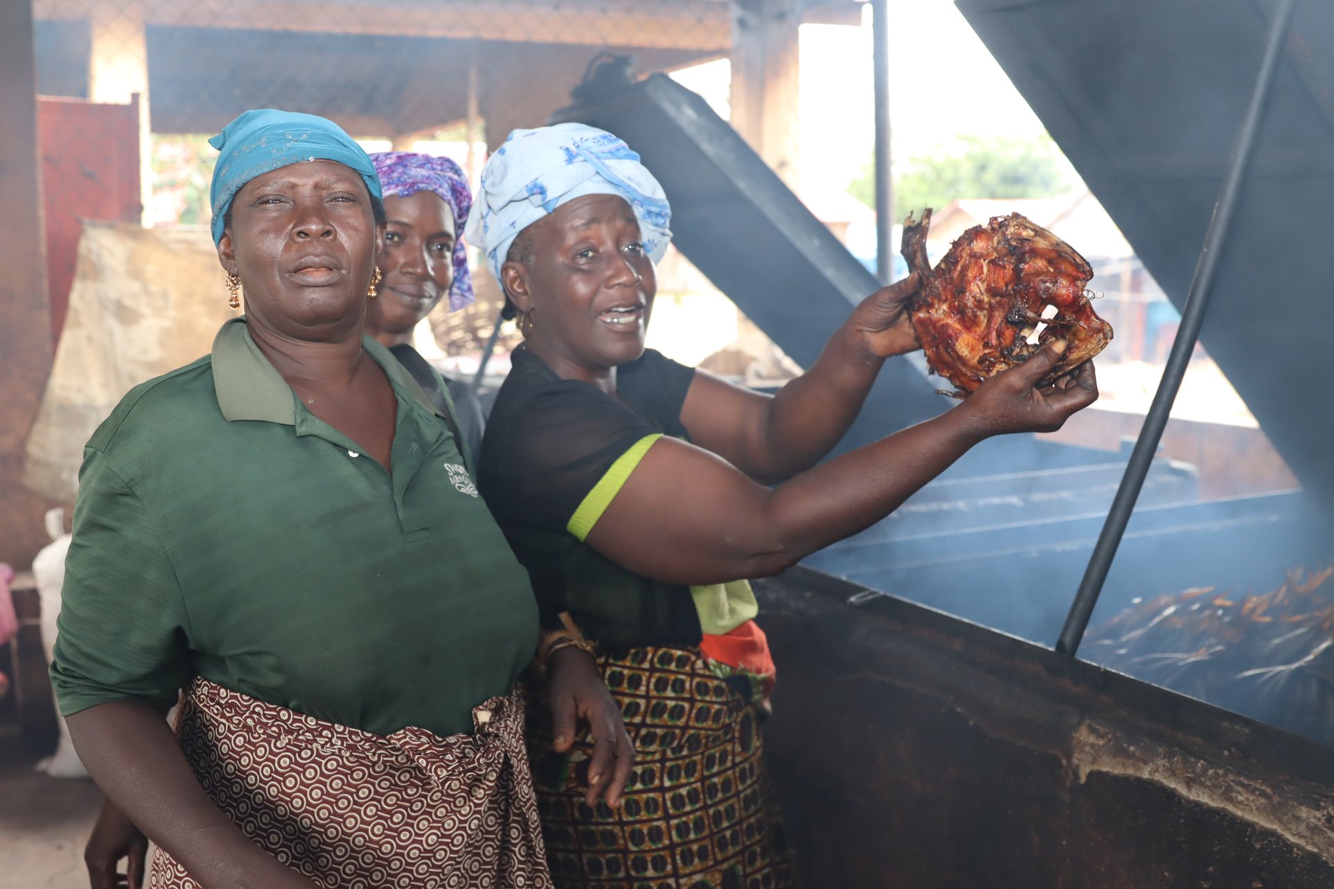 Participants present prepared foods around a large grill.